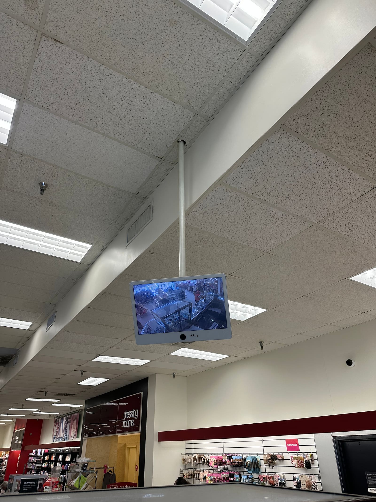 Public-view monitor suspended from a retail store ceiling